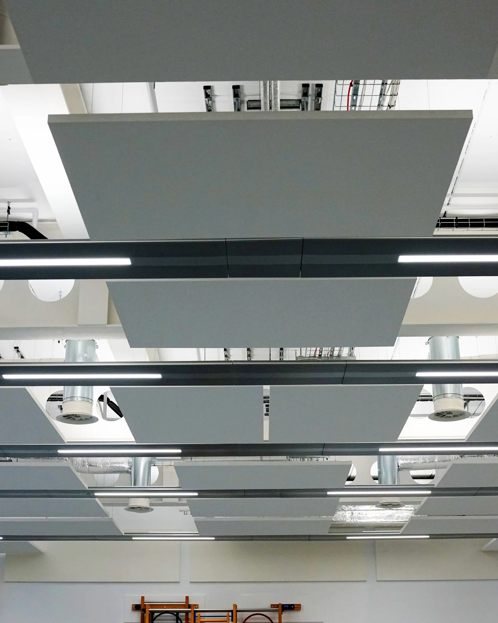 Rows of white suspended acoustic rafts between the ductwork and linear lights in the school hall at St Nicholas School