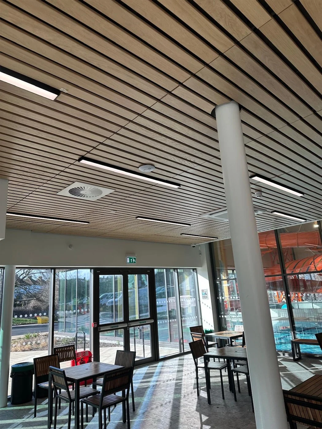 Café with a linear timber slat ceiling and full-height glazing
