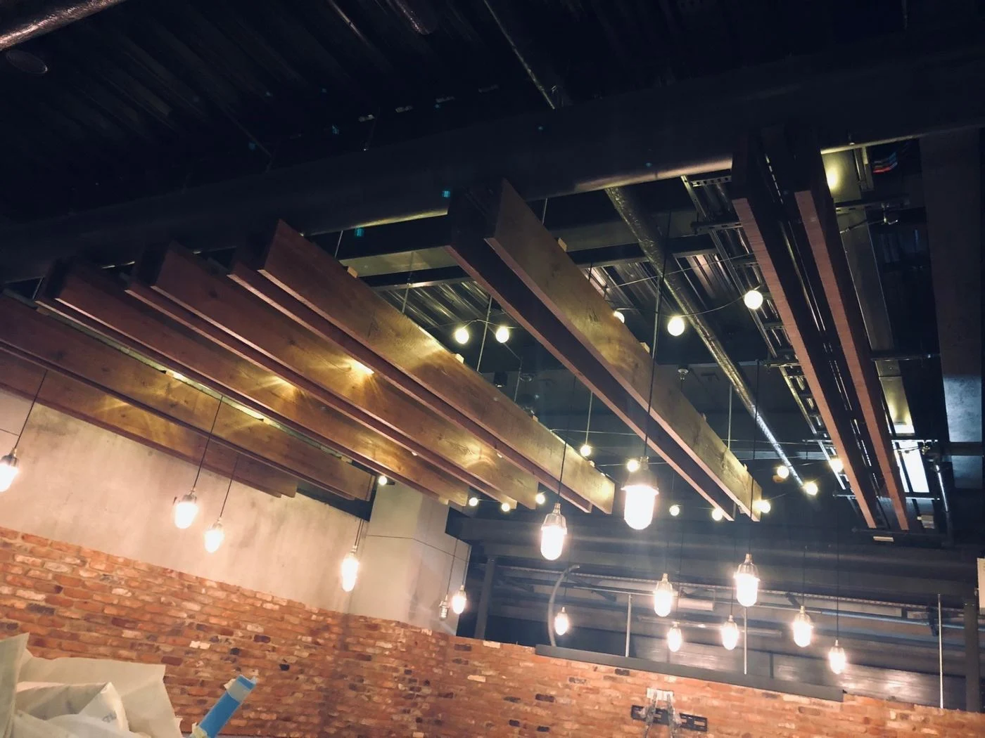 Oak timber rafts and pendant lights over a brick wall inside Twickenham Stadium